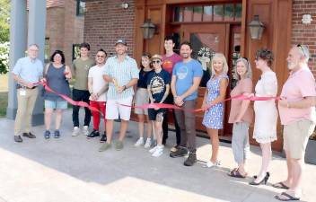 On Aug. 12, Town of Warwick Supervisor Michael Sweeton (left) and members of the Warwick Valley Chamber of Commerce joined Drowned Lands Brewery founder Mike Kraai (center) and his staff to celebrate the first anniversary with a ribbon-cutting ceremony. “The beer we create,” Drowned Lands Brewery founder Mike Kraai said, “takes its cues from the richest soil in the country, connected distinctly to both time and place and inspired by old world techniques and modern innovation.” Photo by Roger Gavan.