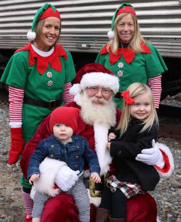 Santa and his elves Michelle Donavan (left) and Sue Hemburi, posed for photos with children like Emily Wihry, 17 months, and her sister Hannah, 3.