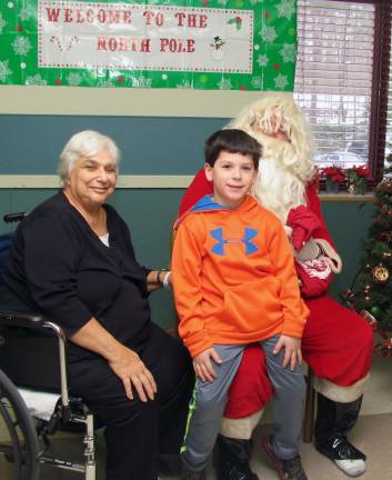 Santa paid an early visit to Schervier Pavilion on Saturday, December 21, and spent several hours posing for photographs with residents and their families while handing out gifts and raffle prizes. Schervier Pavilion resident Nancy Shannon with her grandson Dominick Cosenza, 7, pose for a photo with Santa.