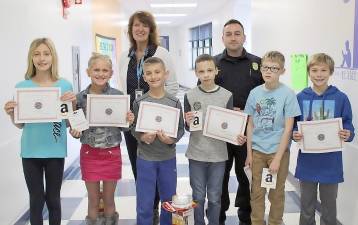 Golden Hill Elementary students Brooke Ehlers, Lauren Scheuermann, Michael Ferko, Dominic Reyes, Kevin Puglisi and Matthew Finnerty celebrate their writing achievements with school Principal Deborah Lisack and Florida firefighter Thomas Andrysak Jr.