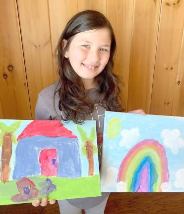 First grader Stella Kambach with her paintings of a pink flamingo and a rainbow with star-shaped clouds. Photo by Tom Bushey/Warwick School District