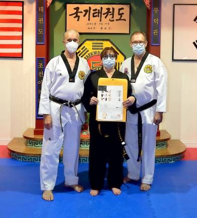 Patti Lurye-Dempster (center), joined by Grandmaster Doug Cook (left) and her husband, Dr. David Dempster, recently earned the 4th degree Master black belt in traditional taekwondo.