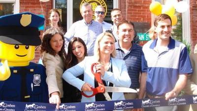 The Orange County Director of Tourism, Amanda Dana, in the company of government officials and Legoland New York's Officer Parks, wields the scissors at the June 21 ribbon cutting for the opening of the Orange County Tourism &amp; Film Welcome Center at 99 Main St. in Goshen.