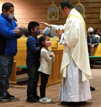 Parochial Vicar Rev. Reynor Santiago blesses young children while serving communion.