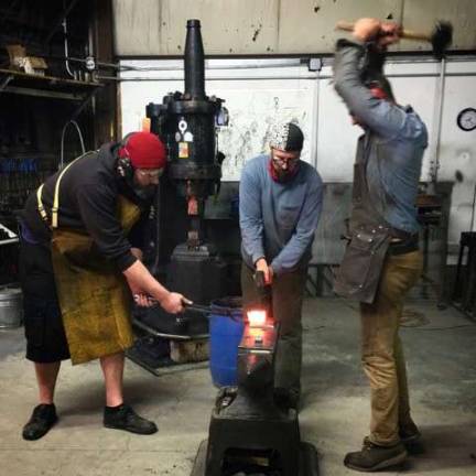 From left to right, Nick Anger, visiting instructor from Vermont, Dave Kurdyla , volunteer from Warwick and Kyle Martin, CMA employee at CMA, hot cutting steel with a striker.