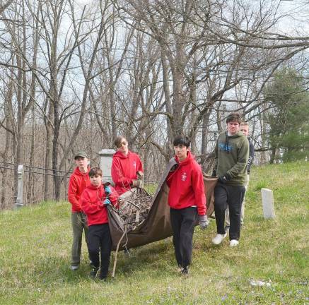 Members of Boy Scout Troop 45 carried a tarp filled with tree branches out of the Amity Cemetery on Saturday.