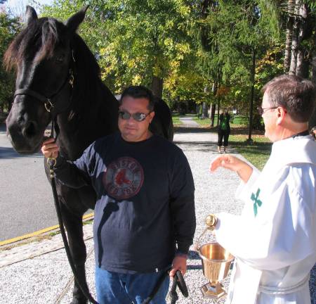 The Rev. Michael McLoughlin blesses &quot;Faco,&quot; a Percheron owned by Tony Aloia.