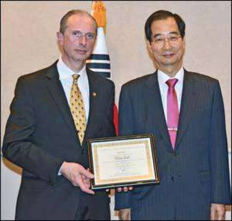 Master Doug Cook accepts taekwondo award from South Korean Ambassador Duk Soo Han