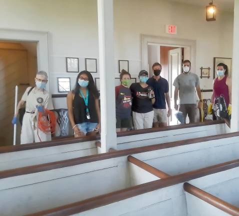 Volunteers pause in their cleaning of the Old School Baptist Meeting House, one of the historic homes and building that the Warwick Historical Society cares for through the year.