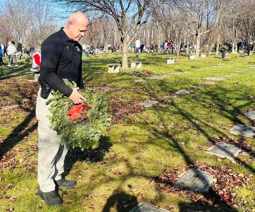 Sheriff Paul Arteta places a wreath on a grave at the Veterans Memorial Cemetery.