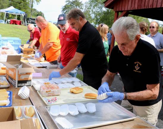 Local officials and other volunteers help fill the trays for hot dogs and later the chicken dinners.