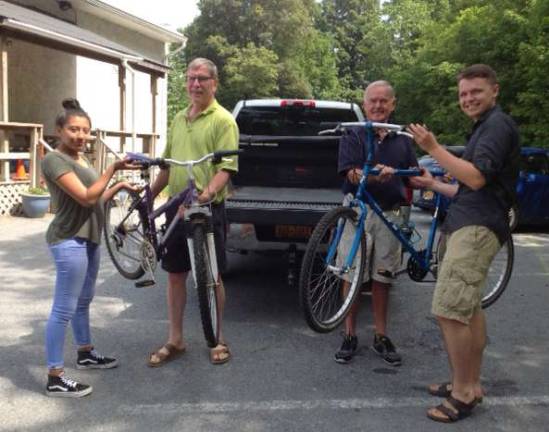 Photo provided by Elizabeth Knight MossZuleica Lopez accepts delivery of a girl's refurbished bike from Sustainable Warwick's Bill Greene. Repair Caf&#xe9; Coach Richard White hands over the second bike that he repaired to Mark Laanineen.