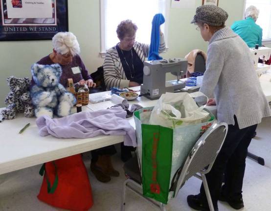 Repair Coaches Joan Bono with custom-made teddy bears and Deanne Singer at her sewing machine assisting Lucy Fischetti