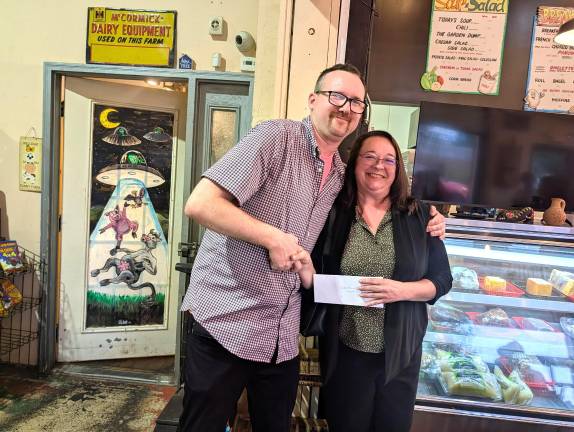 Scenic Farms Leagues Manager Steven DeBuck presents a donation to Ursula Morgan, executive director of Wallkill River Center for the Arts.