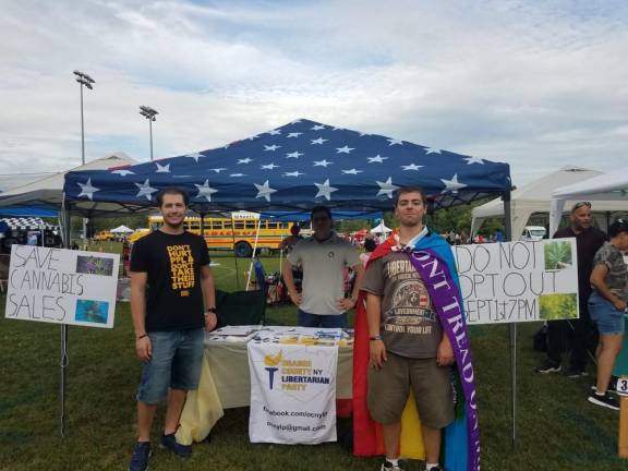 From left: Members of the Orange County NY Libertarian Party, Robert Cocomellow, Mathew Bathrick, and Pietro S. Geraci, wearing the flag, circulating a petition to tell New Windsor to not opt out of recreational cannabis sales and distribution on Aug. 21 at New Windsor Community Day. Photo provided.