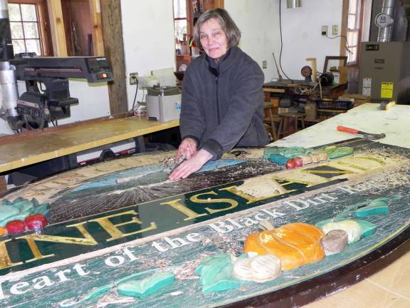 Artisan Susan Bemel works on refurbishing the large hand carved wooden &igrave;Welcome to Pine Island&icirc; sign that normally hangs in the landscaped brick area located at the main intersection in Pine Island. The restoration of the sign was commissioned by the Pine Island Chamber of Commerce through its on-going Beautification Program.