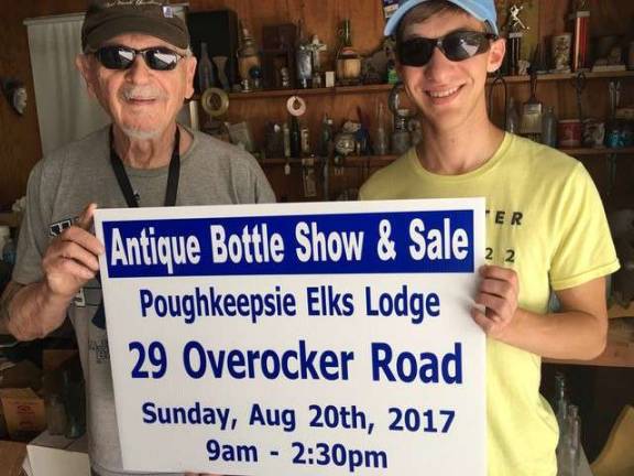 Noted local bottle collectors Jim Jack and Alex Prizgintas hold up one of the Hudson Valley Bottle Club&#x2019;s roadside signs describing the upcoming bottle show. Come out to see the vast amount of antique glassware and bottles.