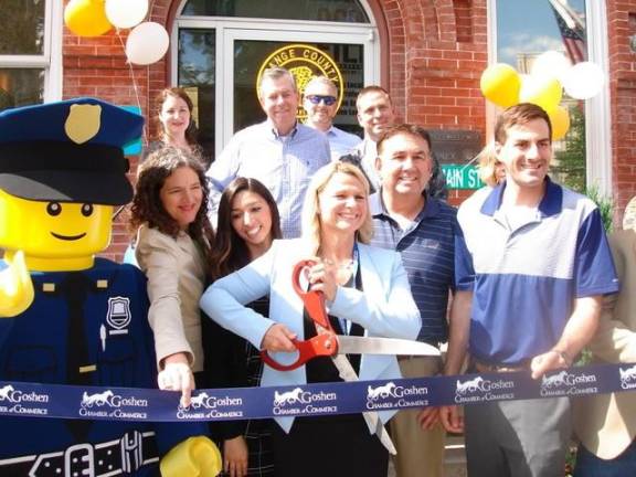 The Orange County Director of Tourism, Amanda Dana, in the company of government officials and Legoland New York's Officer Parks, wields the scissors at the June 21 ribbon cutting for the opening of the Orange County Tourism &amp; Film Welcome Center at 99 Main St. in Goshen.