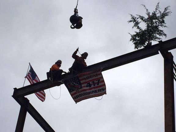 Two Local 417 Ironworkers hoist the beam into place on top of Division 2 (Photo provided)