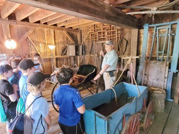 Warwick Historical Society docent Ken Columba shows students an antique tool that was used to cut ice from a lake.