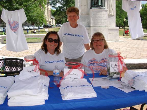 Community members Kim Armistead (left) and Betty Smith (standing) help Therese Urato, co-chair with Joe Betro, organizers of the Goshen Strong Community Picnic, sell T-shirts and magnets at the Goshen Farmers' Market. (Photo by Geri Corey)