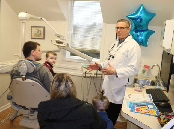 Photos by Roger Gavan Ralph Garcia, holding his son Aidan, 3, and his wife, Erin, with their daughter Kaylee, eight months, listen to dental health suggestions from Dr. Greg Klein on Kids Dental Health Day.