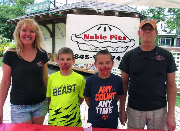 Lorenzo Laneve, 10 (left), and Bradon Scoolidge, 11, pose with Noble Pies owners Leslie Noble and her husband Tom Herman. Bradon was the winner of the children's pie-eating contest.