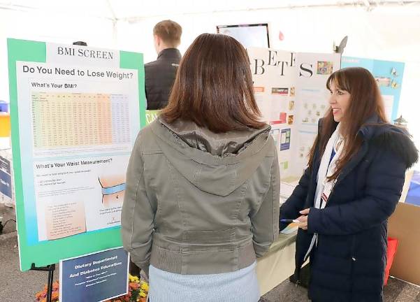 St. Anthony Community Hospital Lead Dietitian Janine Killeen RD, CDE; offers a visitor an opportunity to weigh-in for a body mass index (BMI) evaluation.