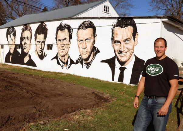 Photo by Roger Gavan Artist Rocco Manno by his mural of well-known Hollywood actors.