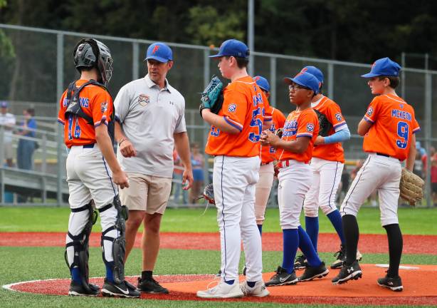 Manager Ray Younghans talks with catcher Zach Younghans and pitcher RJ Kearns as Rylen Mejia, Tom McKeon and others look on during Florida’s July 29 game against Mid Island.