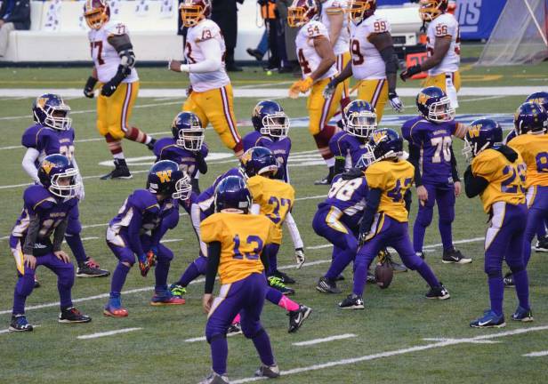 Warwick Youth Football Division 1 offense in purple facing off against the D1 defense in gold with members of the Washington football team watching the action.