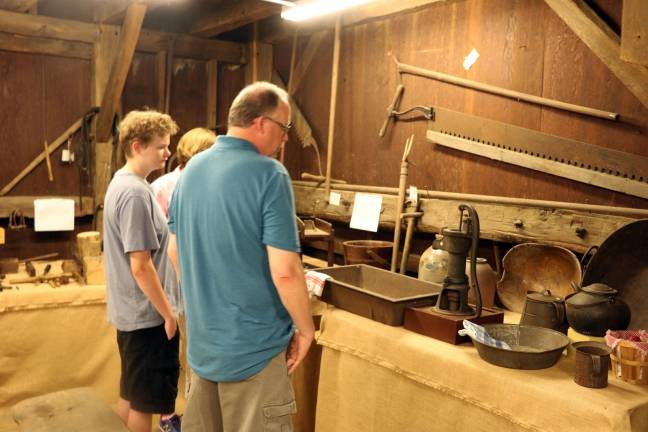 Visitors view the original tools used by early farmers in an agricultural exhibit held in the ca. 1825 Sly Barn that sits behind the Shingle House.