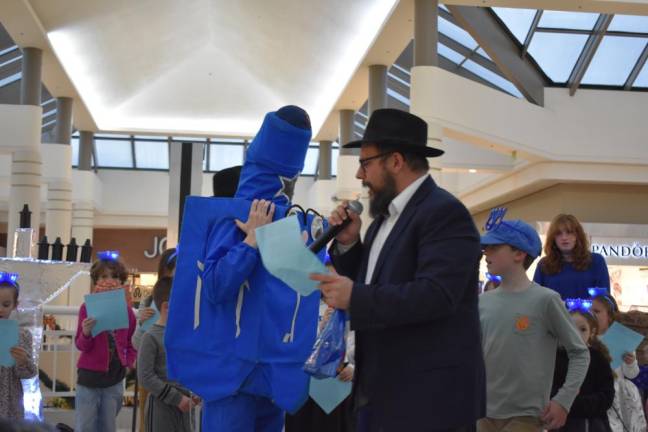 Rabbi Meir leads a line of singing kids around the spinning Dreidel Man.