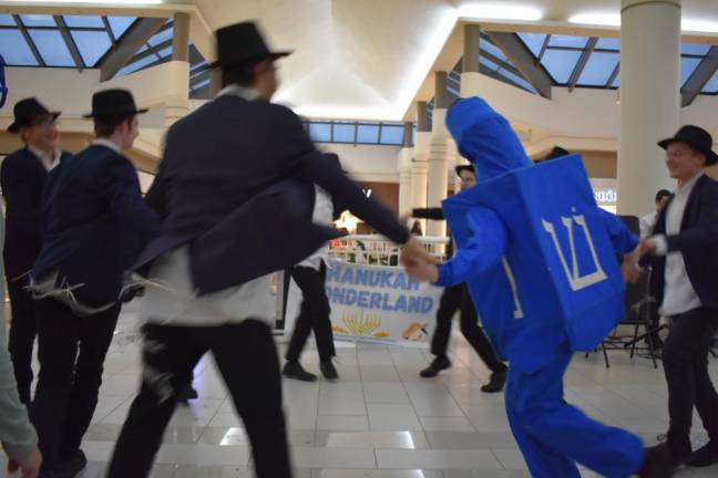 Dreidel Man and a group of boys from a yeshiva shake the floor of the Galleria Mall.