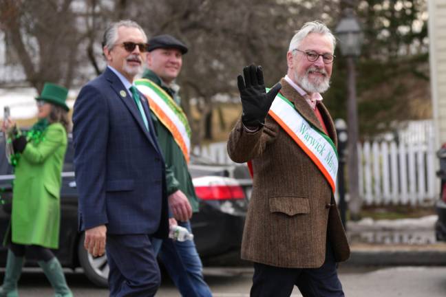 Village Mayor Mike Newhard waves to the crowd during the parade, while Town Supervisor Jesse Dwyer and Town Councilman Tom Mattingly march alongside.