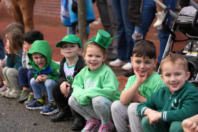 A group of children all decked out in green watch (and enjoy) the parade.