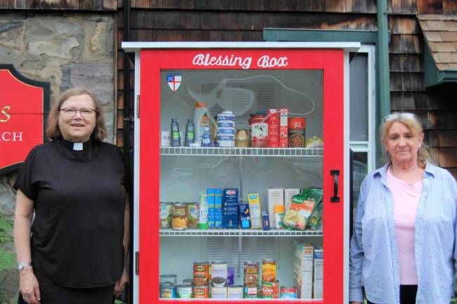 Mother Claire Lofgren (L) and Debby Adams (R) stand next to the church’s Blessing Box.