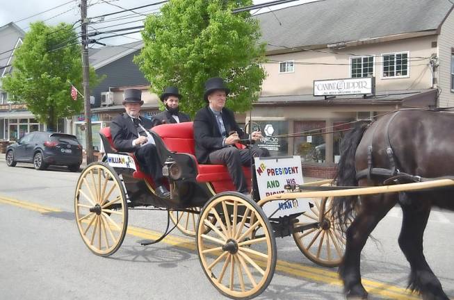 Deputy Mayor Thomas Fuller, dressed as Secretary of State William Henry Seward (left), rides in a horse-drawn carriage with Mayor Daniel Harter, dressed as President Abraham Lincoln.