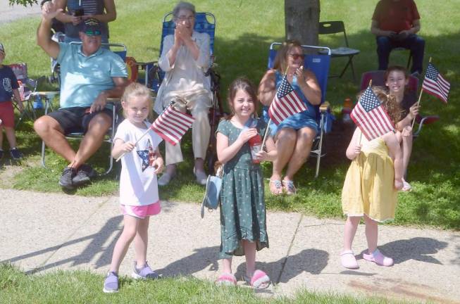 Children waving flags to veterans.