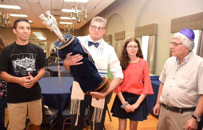 Former Monroe Temple Beth-El President Eben Hill (center) holds one of the Torahs set to travel to Florida, N.Y.
