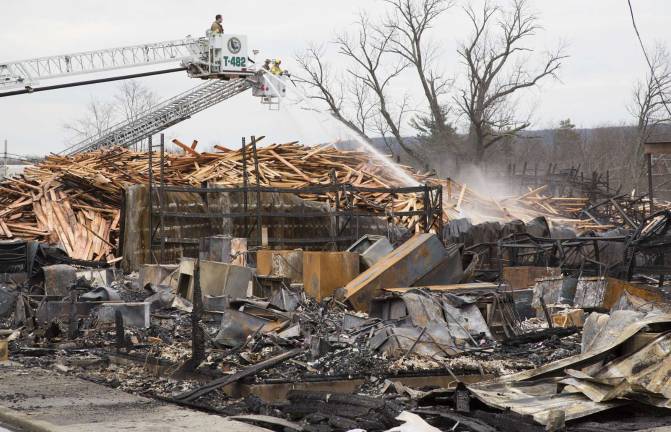 Tower ladders dousing hot spots among the charred ruins and large piles of partially burnt lumber.