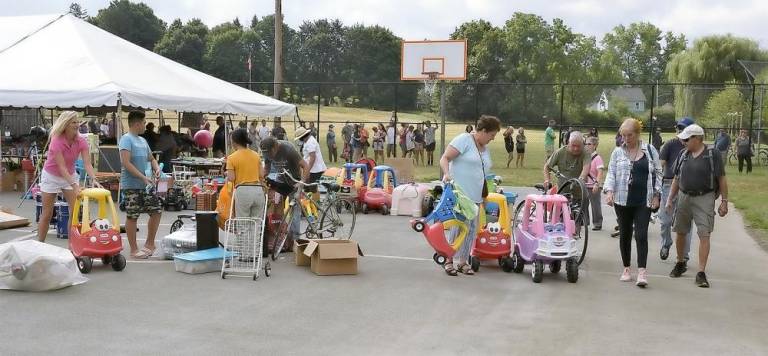 Grownups collected kids’ pedal cars and other toys while folks outside the fence watched the action while waiting their turn to shop.