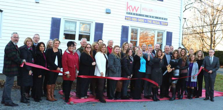 Photo by Roger Gavan On Thursday, November 16, Town of Warwick Supervisor Michael Sweeton (far right), Mayor Michael Newhard (far left) and members of the Warwick Valley Chamber of Commerce joined representatives of Keller Williams and Regal Principal Brokers Patricia Brady (cutting ribbon) and Kim Corkum along with their agents, relatives, friends and business associates to celebrate the merger with a ribbon cutting.
